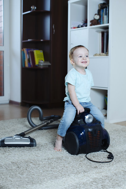 一个非常快乐的婴儿坐在马背上的吸尘器上图片下载