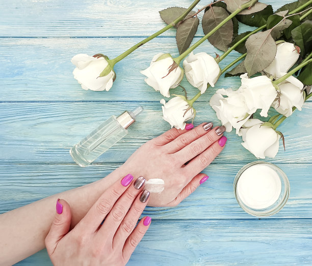 女性的双手，奶油，蓝色木背景上的玫瑰花图片下载