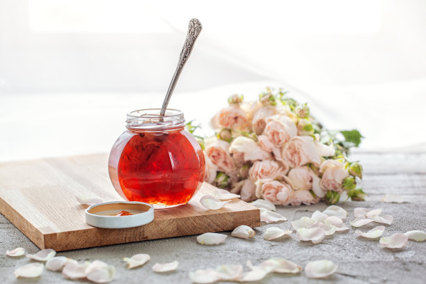 自制玫瑰花瓣果酱和玫瑰花束放在桌上。图片下载