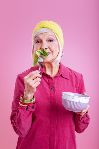 漂亮的老妇人，浓妆艳抹，吃着生菜图片下载