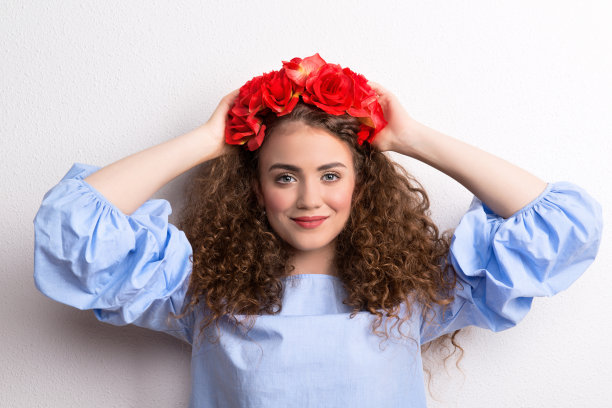 一个正面的年轻美丽的女人与花头巾，手后面的头。图片下载