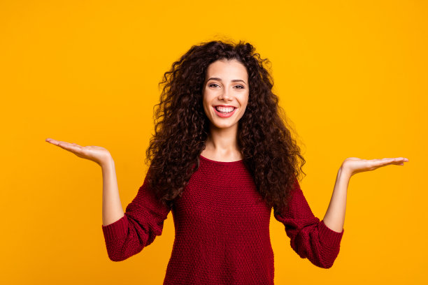 近距离的照片让她惊讶，她的女士双臂张开的手掌呈现新奇的挑选更好的变装，为你穿红色针织毛衣套头衫，衣服，孤立的黄色背景图片下载