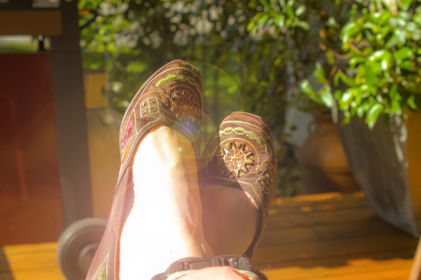 舒适的脚上的图片装饰鞋-女人放松户外与散景背景图片下载