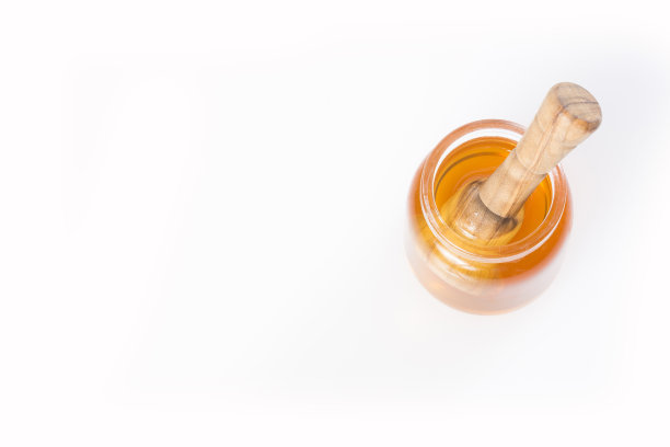 蜂蜜勺和蜂蜜在罐子在白色的背景图片下载