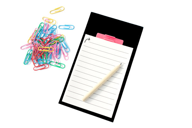 用铅笔在笔记本上，黑色的框架和彩色的剪辑在白色的背景。图片下载