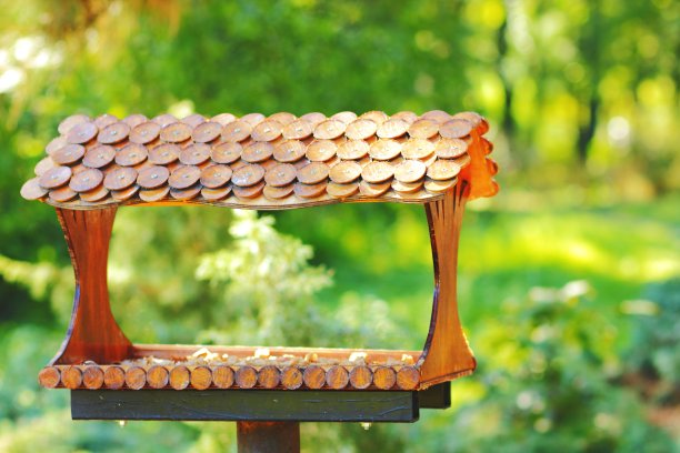 木制喂鸟器。带屋顶的喂鸟器。森林里喂养鸟的房子图片下载