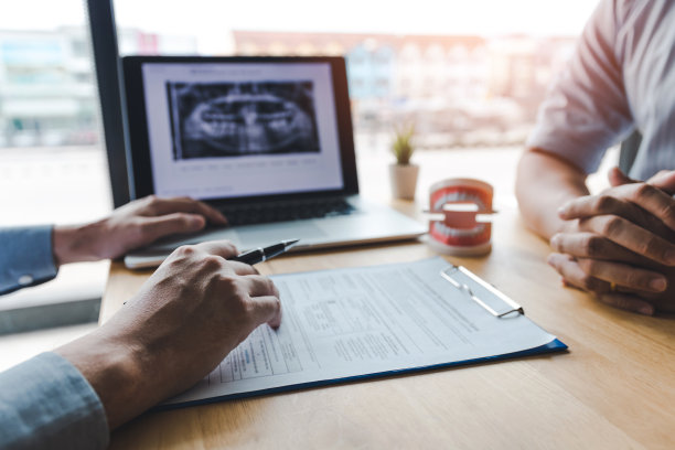 牙科医生正在讨论牙科问题，并在笔记本电脑屏幕上向病人报告x光图像。图片下载