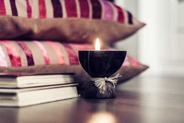 燃烧的温泉芳香蜡烛椰子壳，枕头，格子和书，舒适的家庭内部背景。图片下载