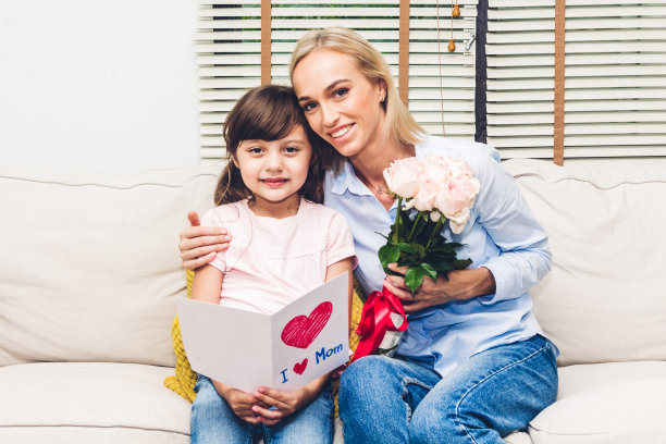 小女儿在母亲节给她妈妈一张贺卡，给她一个惊喜。爱的家庭和母亲节的概念图片下载