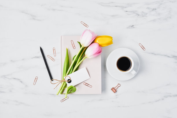 有咖啡杯、郁金香和粉红色日记本的办公桌图片下载