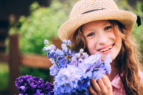 浪漫的肖像快乐的孩子女孩采摘一束美丽的蓝色飞燕草花从夏季花园图片下载