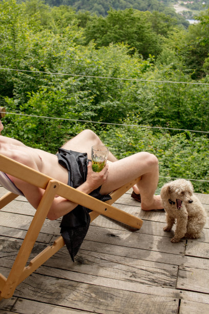 近距离裁剪照片。男人的身体与啤酒和打哈欠纯种狗图片下载