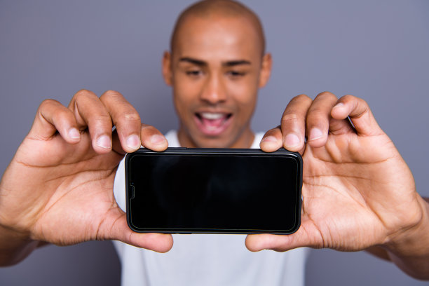 特写照片有吸引力的深色皮肤，他，他，他，他的男子短发，使自拍在主电话摄像头是的是的，面部表情，穿着白色的t恤，外套，衣服孤立的灰色背景图片下载