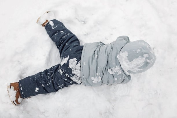 蹒跚学步的小男孩在雪中玩耍图片下载