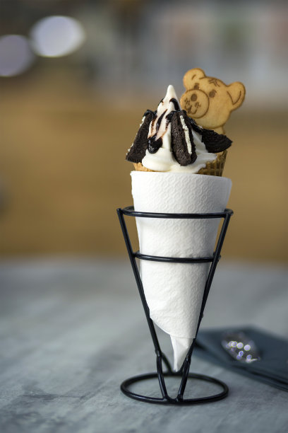 白色盘子和冰淇淋甜点在威化杯与巧克力饼干和创意装饰顶部模糊彩色的室内背景。图片下载