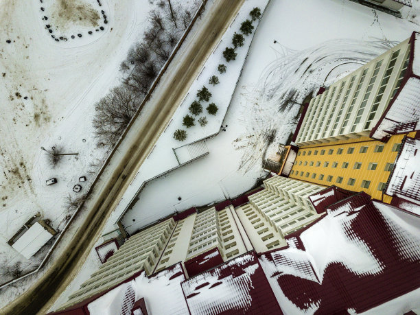 在狭窄肮脏的道路和雪域郊区现代大公寓楼的冬季高空视图。图片下载