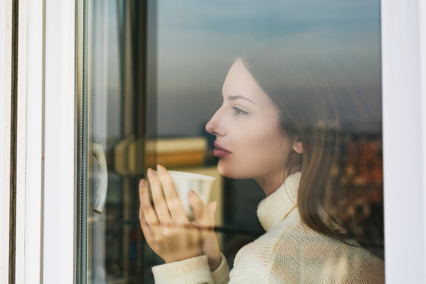 年轻女子喝着咖啡，看着窗外图片下载
