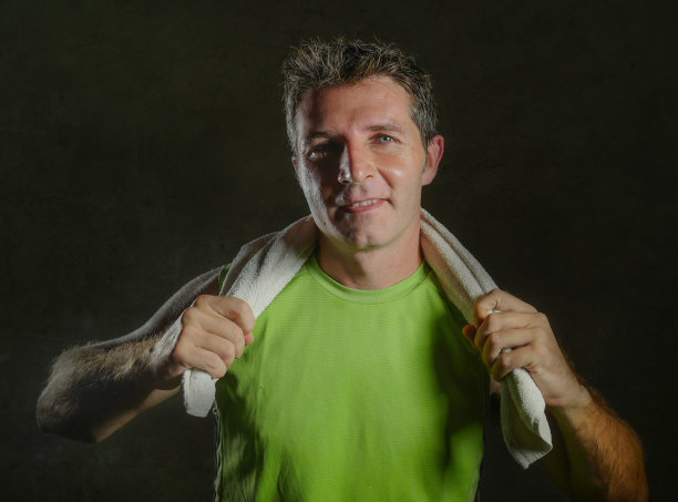 年轻快乐和有吸引力的30多岁或40多岁流汗的男人在健身俱乐部训练后微笑，锻炼感觉满意，拿着健身毛巾孤立在黑色背景的健康生活方式的概念图片下载