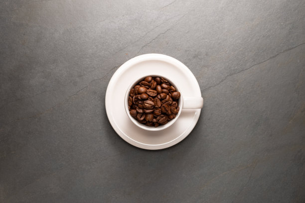 顶视图照片的咖啡杯装满了咖啡豆和碟在一个石头的背景图片下载