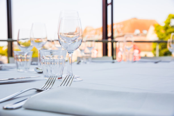在全景窗口前，一张铺着白色桌布的桌子上放着空杯子图片下载