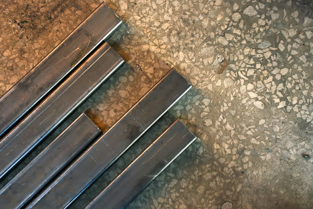 管道的金属型材放在车间的混凝土地板上。工业背景的金属结构的实施。图片下载