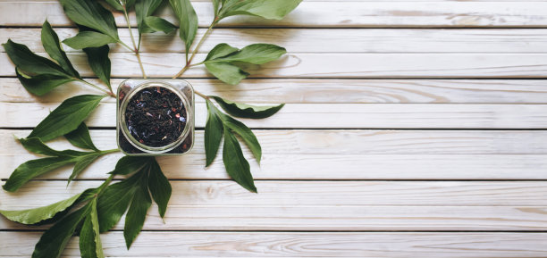 玻璃杯中的干红茶，木色背景，牡丹绿叶。红茶。草本植物。图片下载