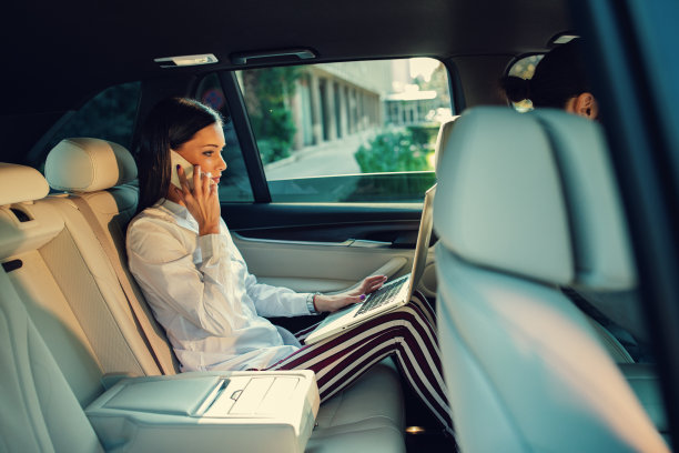 女商人在轿车后座跟电话聊天图片下载