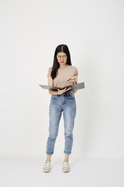 可爱的黑发女孩拿着一支钢笔和一本白色的书图片下载