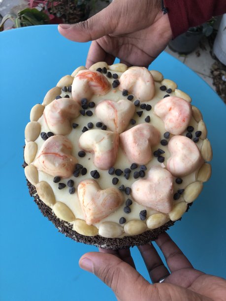 这是在花园里手持巧克力橙蛋糕/海绵蛋糕/蛋糕的照片，上面有奶油、奶油、巧克力屑和爱心图片下载