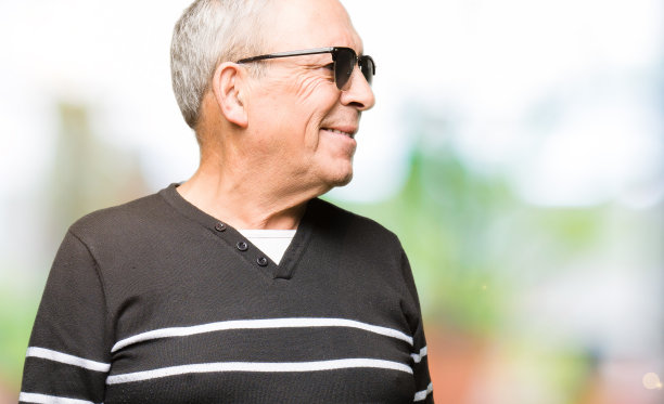 帅气的老男人穿着冬天的毛衣和太阳镜看向一边，脸上带着微笑，表情自然。自信的笑。图片下载