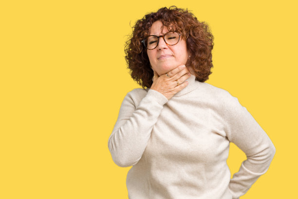 美丽的中年老年妇女穿着高领毛衣和眼镜在孤立的背景触摸疼痛的脖子，喉咙痛的流感，感冒和感染图片下载