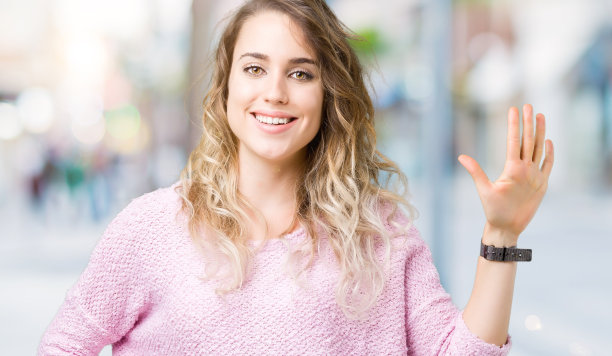 美丽的年轻的金发女人在孤立的背景显示和指向第五个手指，同时自信和快乐的微笑。图片下载