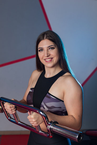 美丽的女孩在健身房的地板上用杠铃锻炼肱二头肌图片下载