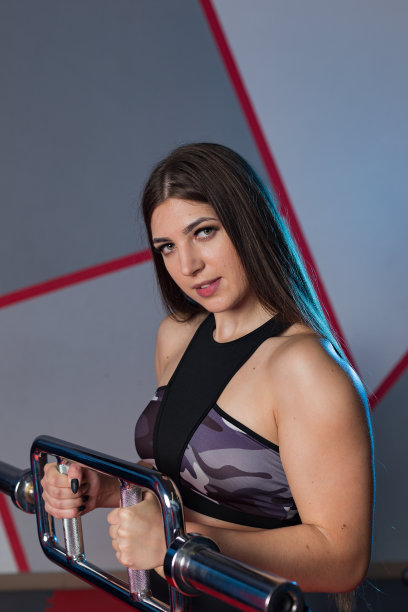 美丽的女孩在健身房的地板上用杠铃锻炼肱二头肌图片下载