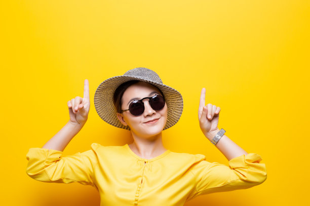 肖像女人戴墨镜和帽子指向上方复制空间孤立的黄色背景图片下载