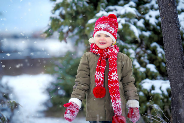 可爱的小男孩穿着五颜六色的衣服在下雪的时候在户外玩耍。在冬天寒冷的雪天与孩子们积极的休闲活动。快乐的孩子玩得开心，玩雪图片下载