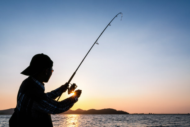一个年轻人在湖边钓鱼。图片下载