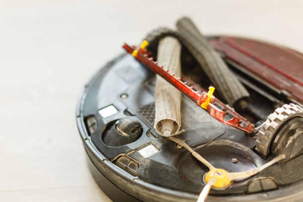 强化木地板上的机器人真空吸尘器，客厅里的智能机器人自动无线清洁技术机器-部分侧刷。图片下载