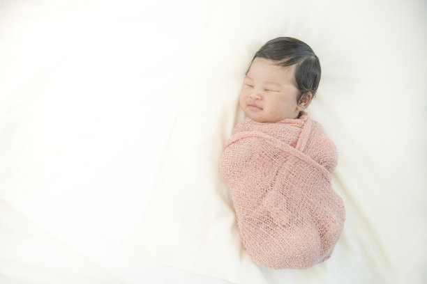 新生儿睡在白色背景的床上图片下载