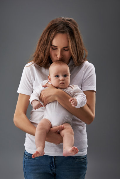 迷人的母亲吻着婴儿的头，闭上眼睛图片下载