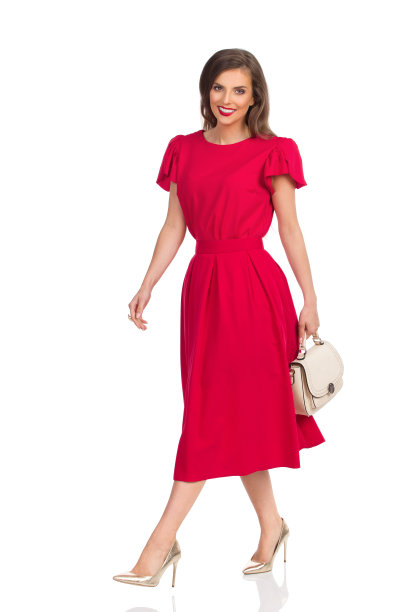 微笑的女人在红色的裙子，金色的高跟鞋和米色的钱包正在走图片下载