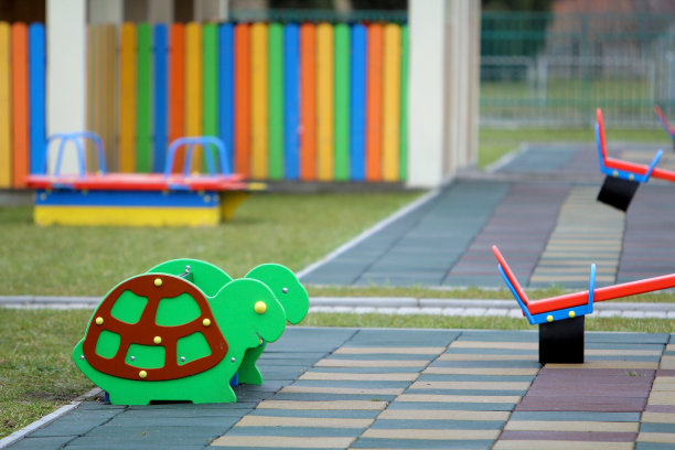在阳光明媚的夏日里，幼儿园操场上明亮的彩色有趣的长椅和柔软的橡胶地板。儿童户外活动和娱乐活动。图片下载