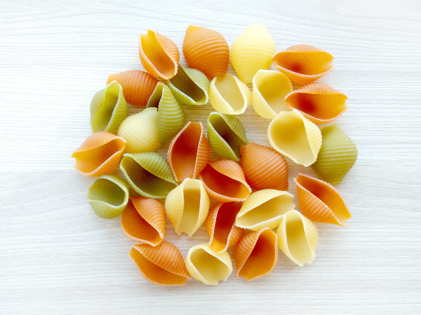 质感丰富的意大利食物——木桌上五颜六色的生贝壳意面图片下载
