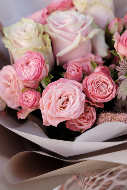 一束白色和粉红色的玫瑰。女人花商拿着一束花在室内。女花匠在花店准备花束。关闭了。副本的空间。母亲节和情人节的概念图片下载