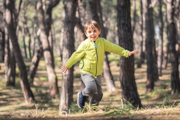快乐的小男孩在森林里奔跑图片下载