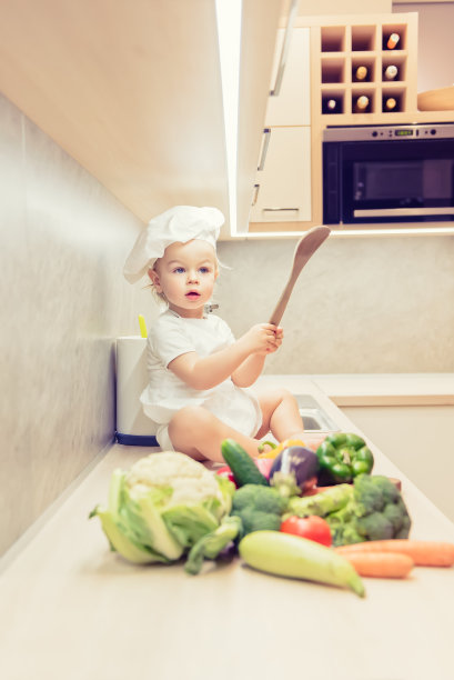小男孩坐在厨房的蔬菜中间准备做饭图片下载