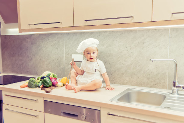 小男孩坐在厨房的蔬菜中间准备做饭图片下载