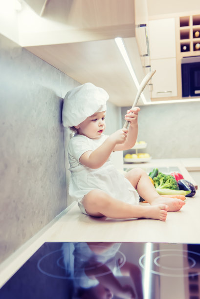 小男孩坐在厨房的蔬菜中间准备做饭图片下载