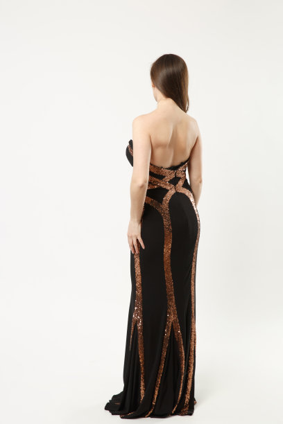 全身照片的时装模特女人穿着优雅的晚礼服黑色礼服摆姿势孤立的白墙背景工作室肖像。黑发长发的女孩。模拟拷贝空间。后视图。图片下载