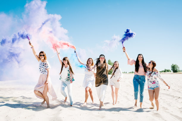 美丽快乐时尚性感的年轻女孩站在海滩上，举起彩色烟雾弹。烧毁。真诚的微笑。波西米亚风格的派对。少女晚上派对。未婚女子。关闭了。肖像图片下载